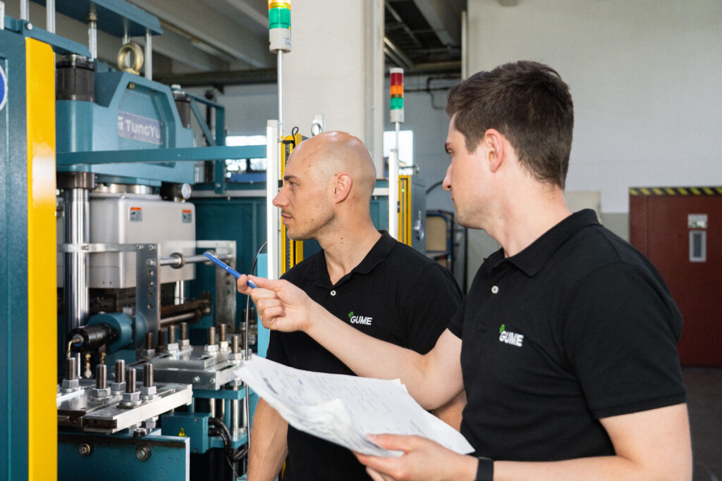 Die beiden Geschäftsführer der GUME im Austausch bei einer Pressmaschine.
