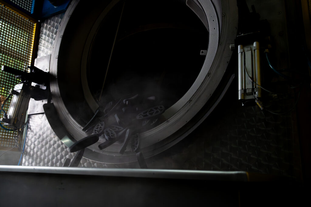 Geöffnete Gefrierentgraten-Maschine aus der entgratete Gummiformteile herausfallen.